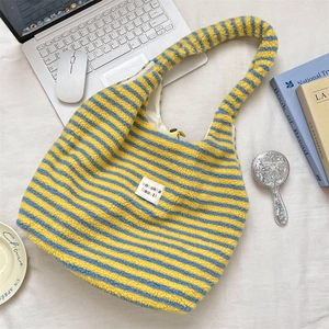 Detailansicht der flauschigen Streifen-Tasche mit gelbem Druckknopf und Logo-Etikett