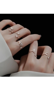 Close-up of adjustable silver rings with pavé zircon initials H, V, W, L and C