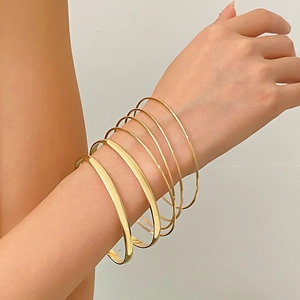 Macro shot of 7-piece minimalist gold stackable bracelet set on female wrist
