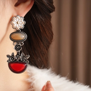 Close-up of vintage drop earrings featuring white flower and red gemstone detail