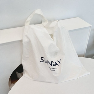 Detail of white canvas tote bag with Sunday Summer Night Pajama blue letter print