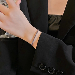 Detail of silver bracelet with purple zircon oval stones on model wrist with black suit