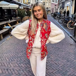 Ethnic style red floral quilted vest paired with a cream knitted sweater in an outdoor setting