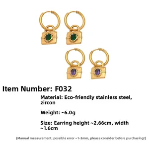 Détail macro de boucles d'oreilles cadenas dorées serties de zircons verts et violets