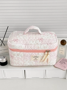 Detailed macro of pink quilted floral makeup bag with ribbon zipper pull and bow patterns