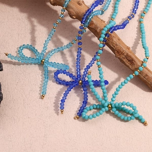 Three beaded bow necklaces with blue faceted crystal beads on natural wood background