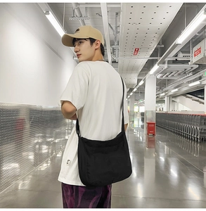 Detailed view of a large black nylon crossbody bag worn by a model in a casual setting