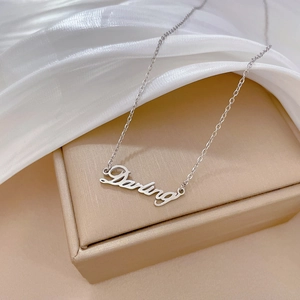Macro detail of silver Darling script pendant necklace on silk fabric and gift box