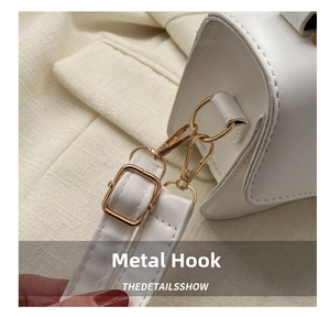Detail of high-quality gold metal hooks and adjustable buckle on white leather handbag