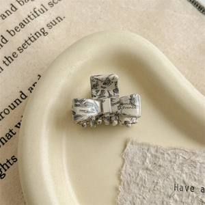 Detailed close-up of marble pattern acetate bow hair claw with gold French lettering