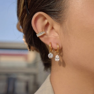 Close-up of gold stainless steel hoop earrings and ear cuff with sparkling zircon drops