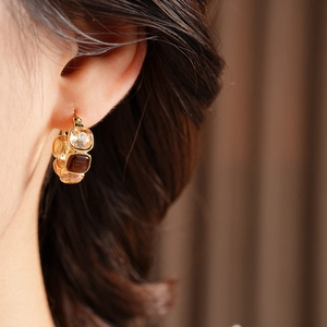 Close-up of vintage resin geometric earrings on model featuring amber and brown tones