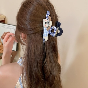 Détail d'une pince à cheveux en peluche à carreaux bleus avec chien teckel sur cheveux