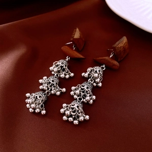 Detailed close-up of ethnic style earrings with wooden elements and silver metal tassels