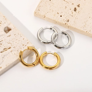 Close-up of gold and silver chunky hoop earrings on a stone textured surface