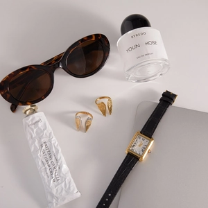 Flat lay of gold and silver wing-shaped stainless steel rings in a luxury setting
