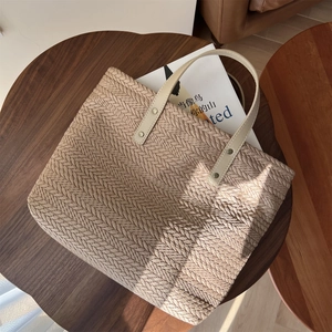 Handwoven beige canvas tote bag with herringbone pattern and cream leather handles