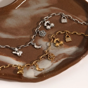 Stainless steel charm bracelet featuring moon flower cherry and tassel pendants in gold and silver