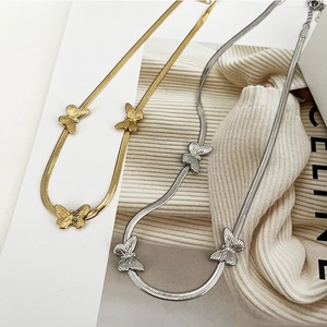Flat butterfly necklaces in gold and silver steel on minimalist chic background