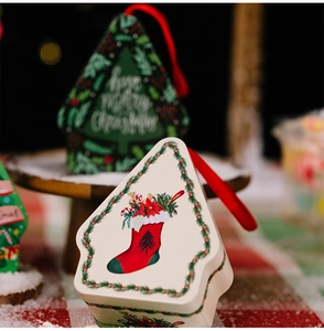 Macro view of house-shaped Christmas tin gift box with vintage stocking print and red lanyard