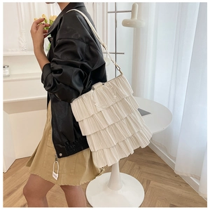 Detail of white pleated ruffle shoulder bag with a modern clear acrylic round handle