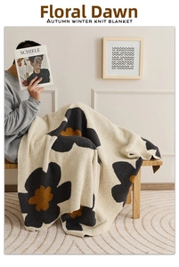 Detail of a thick knitted blanket with grey sunflower patterns in a cozy home setting