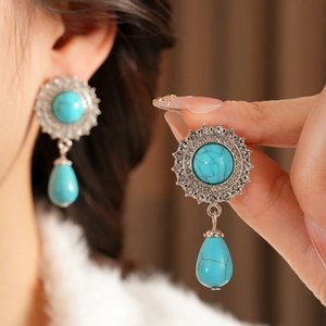 Macro shot of vintage silver earrings with teardrop turquoise and sparkling crystal pavé