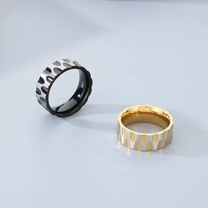 Macro detail of wave texture on stainless steel rings with gold and black grooves