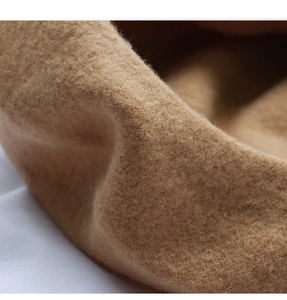 Detailed macro view of soft camel wool felt texture on a warm minimalist beret hat