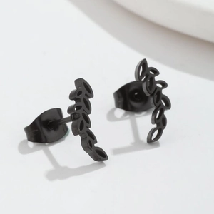 Macro detail of black branch leaf stud earrings with realistic plant texture on white background