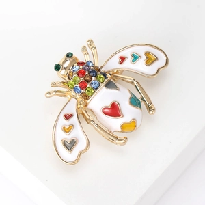 Macro shot of bee brooch with white enamel wings and colorful rhinestones on gold metal