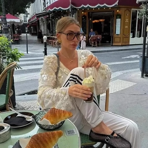 Elegant white V-neck shirt with sequin patches and three-stripe jogger pants in a street setting