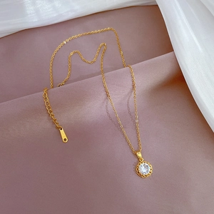 Elegant gold plated titanium necklace with round zircon pendant on soft silk background