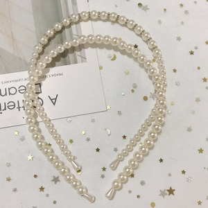 Detail view of pearl and rhinestone headbands set on soft white sequin mesh background