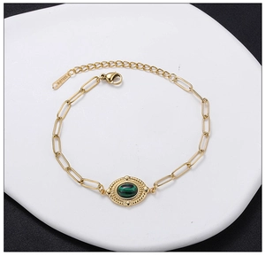 Macro detail of gold stainless steel paperclip chain bracelet with green turquoise stone