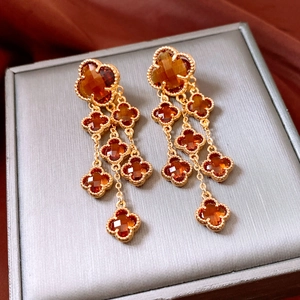 Detailed macro view of 18k gold plated clover tassel earrings with amber glass stones