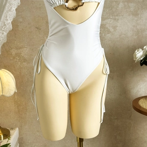 Close-up of white cutout swimsuit with golden ring and side drawstring details