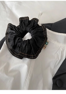 Detailed shot of premium black denim scrunchie with contrast stitching and woven label