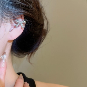 Dettaglio di un ear cuff a fiocco argento con zirconi indossato sulla cartilagine
