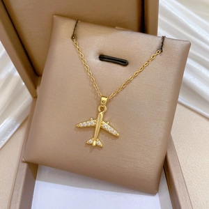 Macro detail of gold airplane pendant with crystal accents on a jewelry cushion