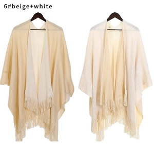 Dettaglio scialle in maglia beige e bianco con trama morbida e orlo con frange lunghe