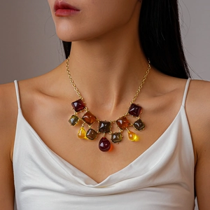 Gros plan d'un collier bohème avec pendentifs géométriques en résine ambre et bordeaux