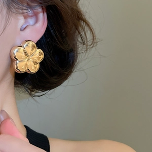 Close-up of elegant gold flower stud earring with polished mirror finish on model