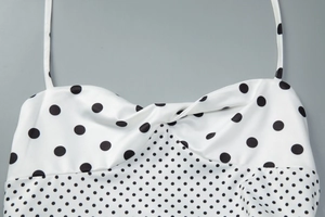 Dettaglio del design del petto annodato e del motivo a pois neri sull'abito bianco