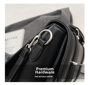 Detailed macro view of silver metallic buckle on black lychee grain leather handbag