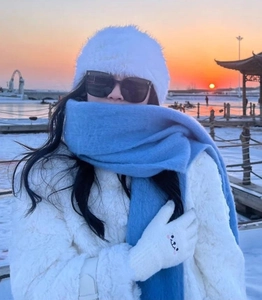 Detailed view of white plush hat, blue scarf, and embroidered gloves for winter warmth