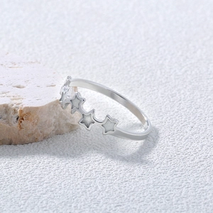 Macro detail of silver star ring with white enamel inlay on a textured stone surface