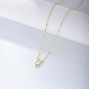 Macro detail of a minimalist gold S925 silver necklace featuring a square zircon pendant