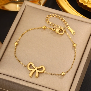 Detailed shot of golden bow charm bracelet with bead accents on jewelry display