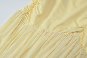 Detail of waist ruffles and mesh stitching on pale yellow off-shoulder dress